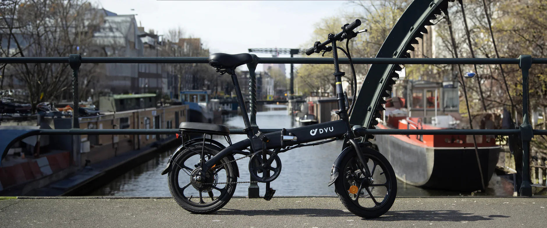 DYU A1F electric bike on a bridge with canal and cityscape in the background